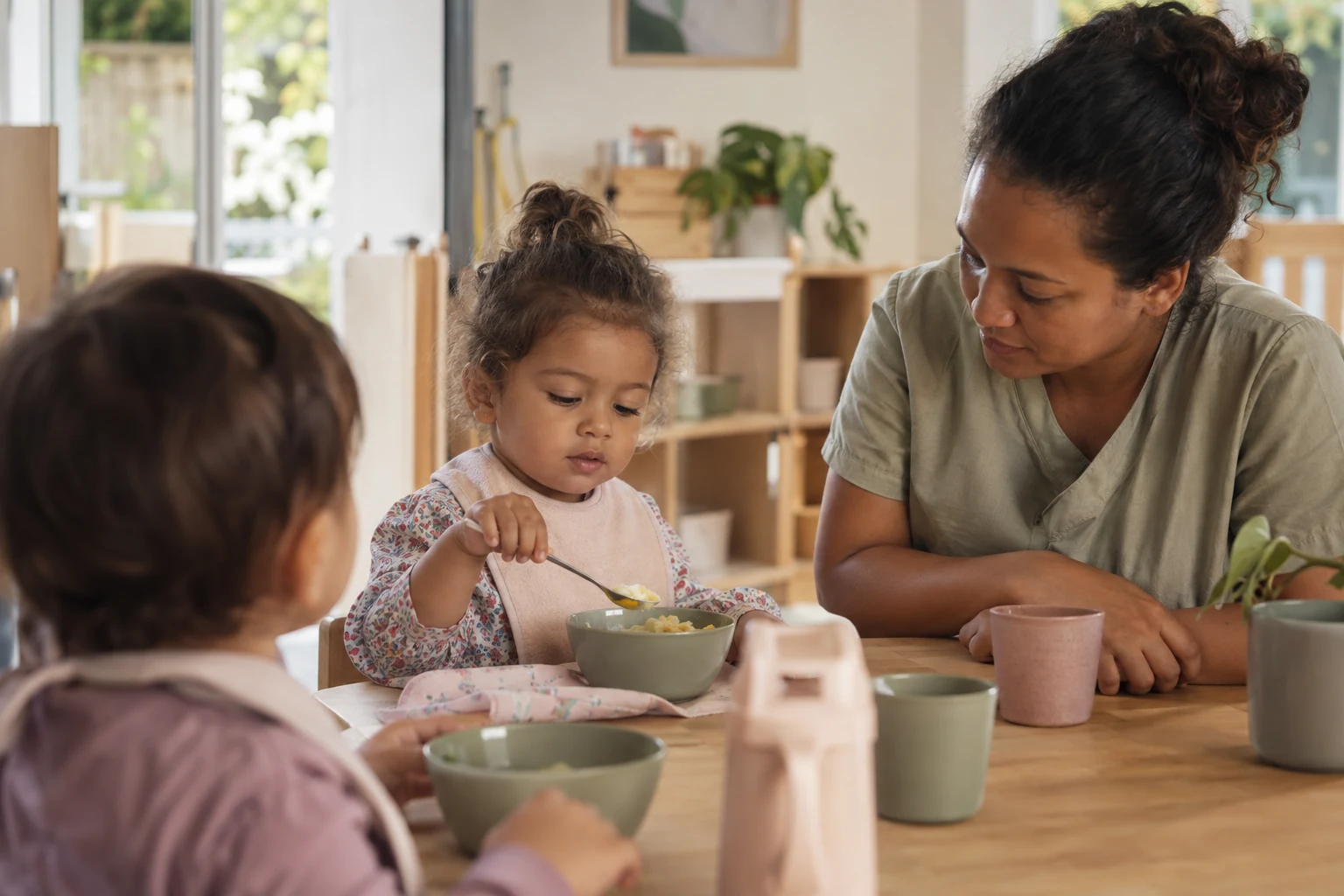 Un jeune enfant essaie de manger seul, accompagné à table, scène générée